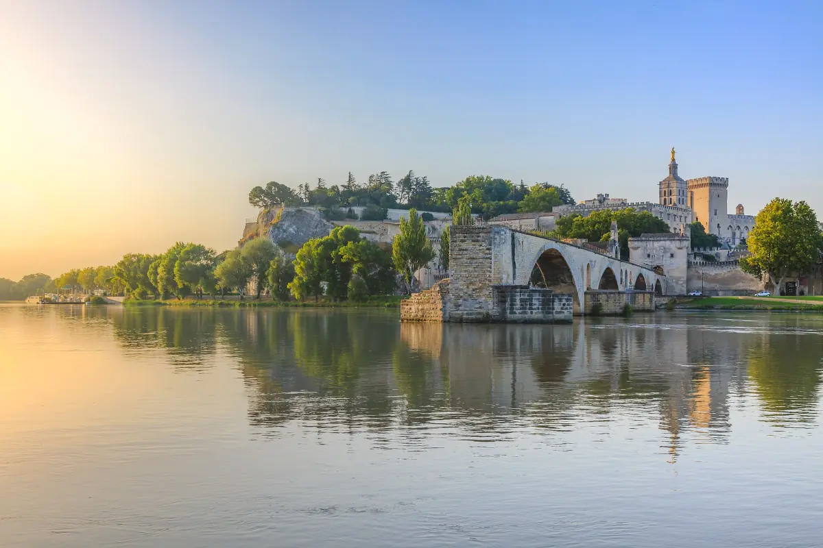 Avignon skyline with the papal palace and broken bridge reflected in the Rhône at sunrise