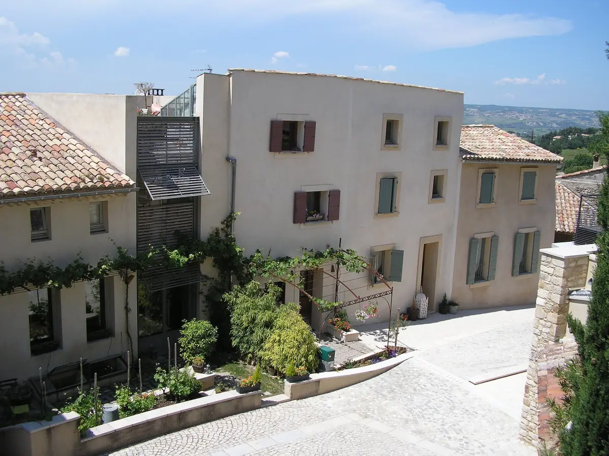 Sunny village square in Gigondas lined with pale stone houses and a few trees