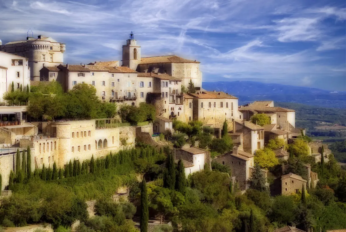Stone houses of Gordes stacked on a hillside under a pale sky with thin cloud