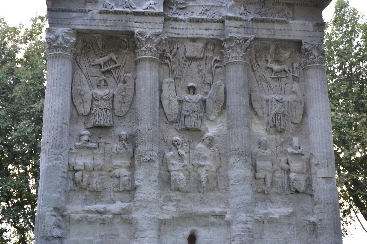 Roman triumphal arch of Orange with carved relief panels beside green trees
