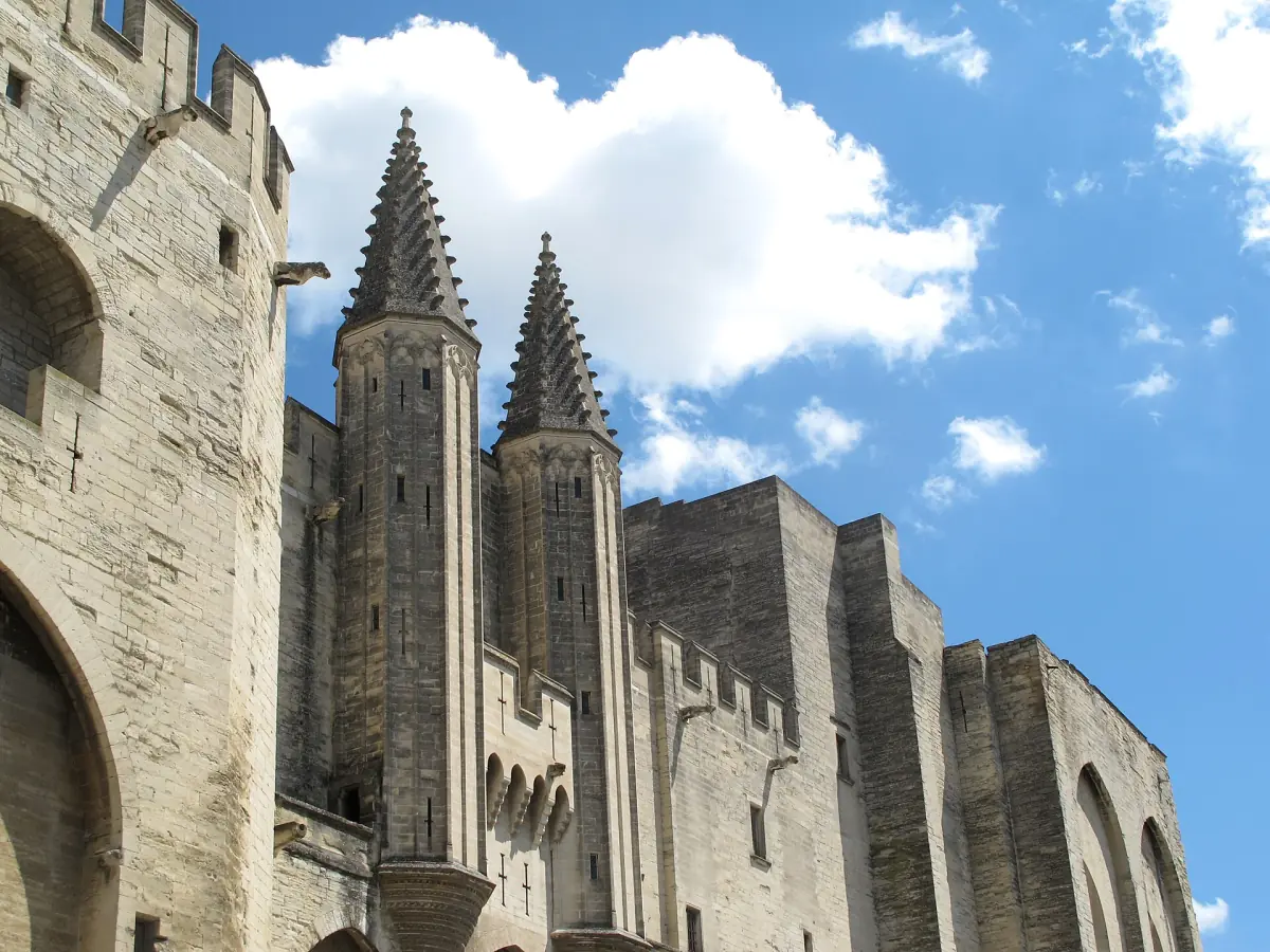 Pointed towers of the Palais des Papes against a blue sky with light clouds