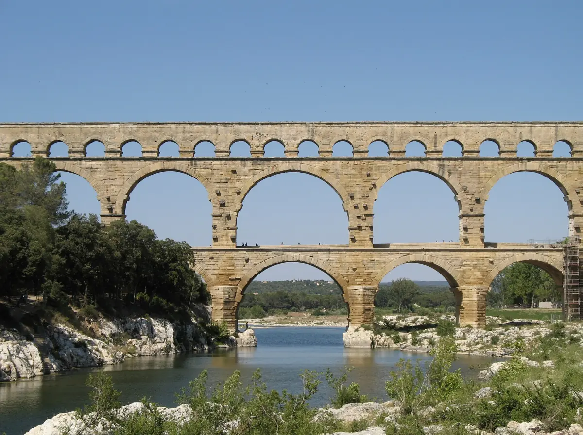 Three tiers of Roman arches of the Pont du Gard spanning a green river valley