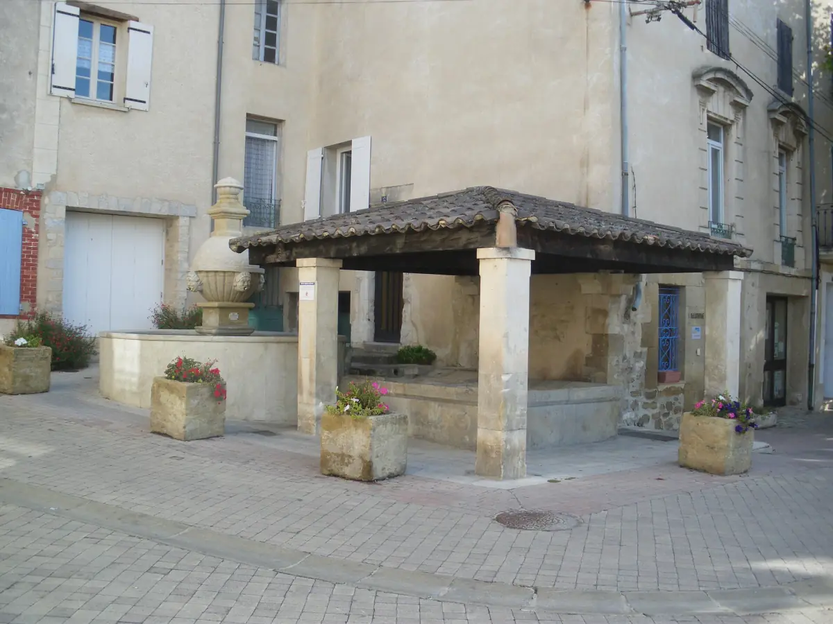 Covered stone fountain on a quiet paved square in the village of Sablet