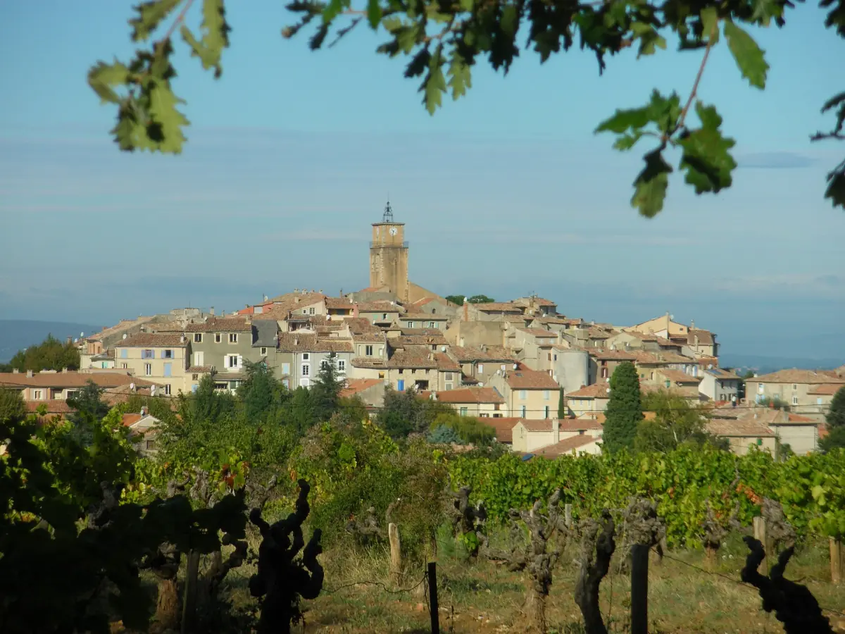 Hilltop village of Sablet with a bell tower rising behind rows of vines